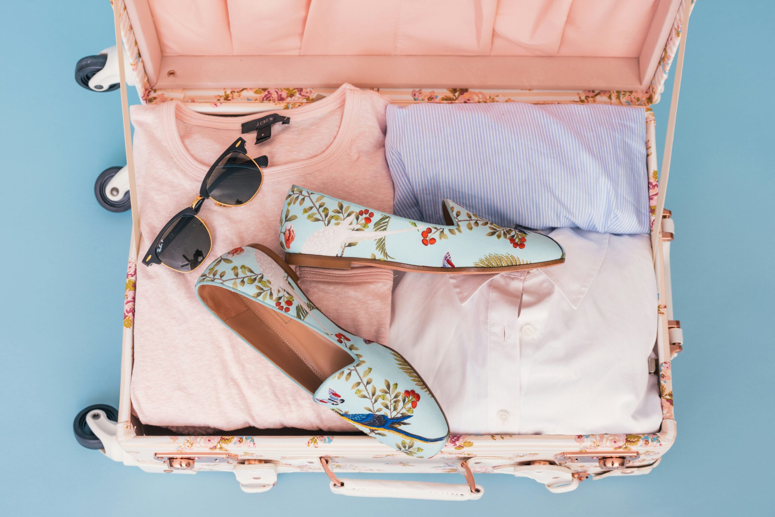 A sleek pair of compact travel nail clippers lying next to a passport and sunglasses