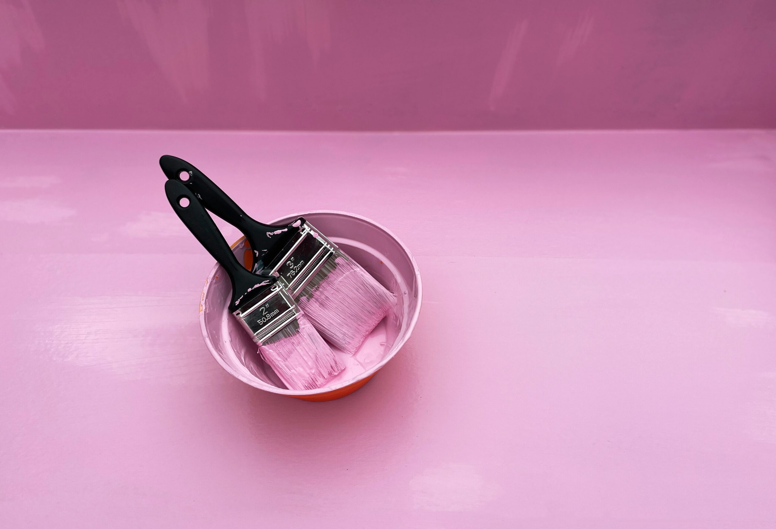 Three types of nail clippers laid out on a pink background