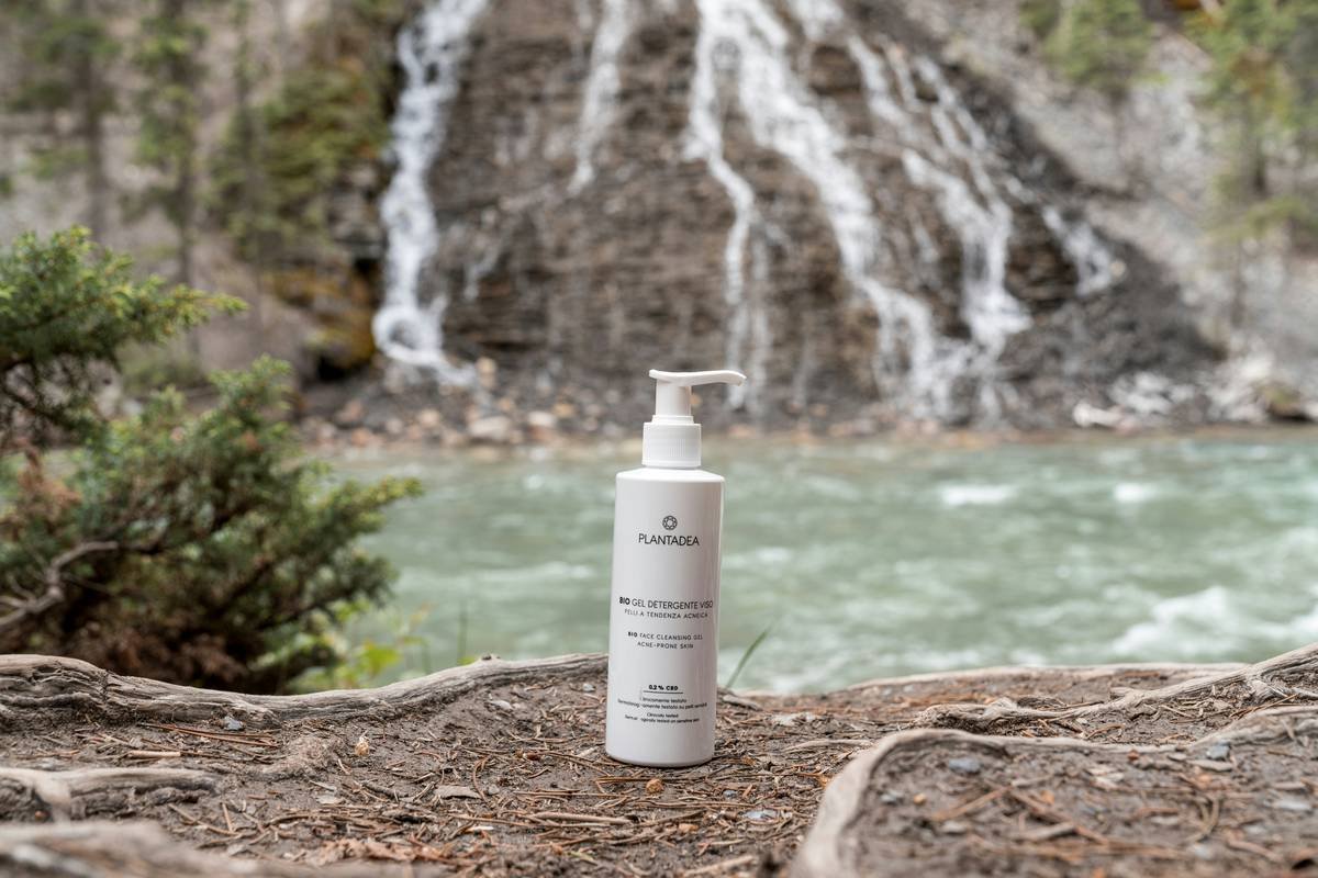a bottle of lotion sitting on a rock next to a waterfall