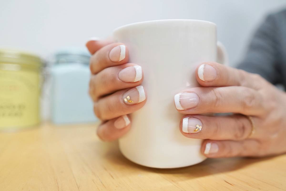A lady with polished nails holding a cup