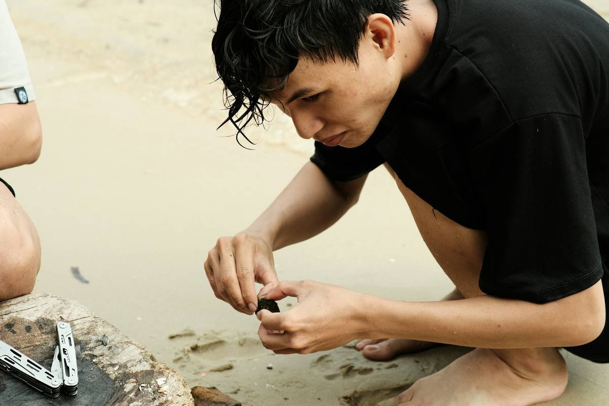 a man sitting on the ground working on a cell phone