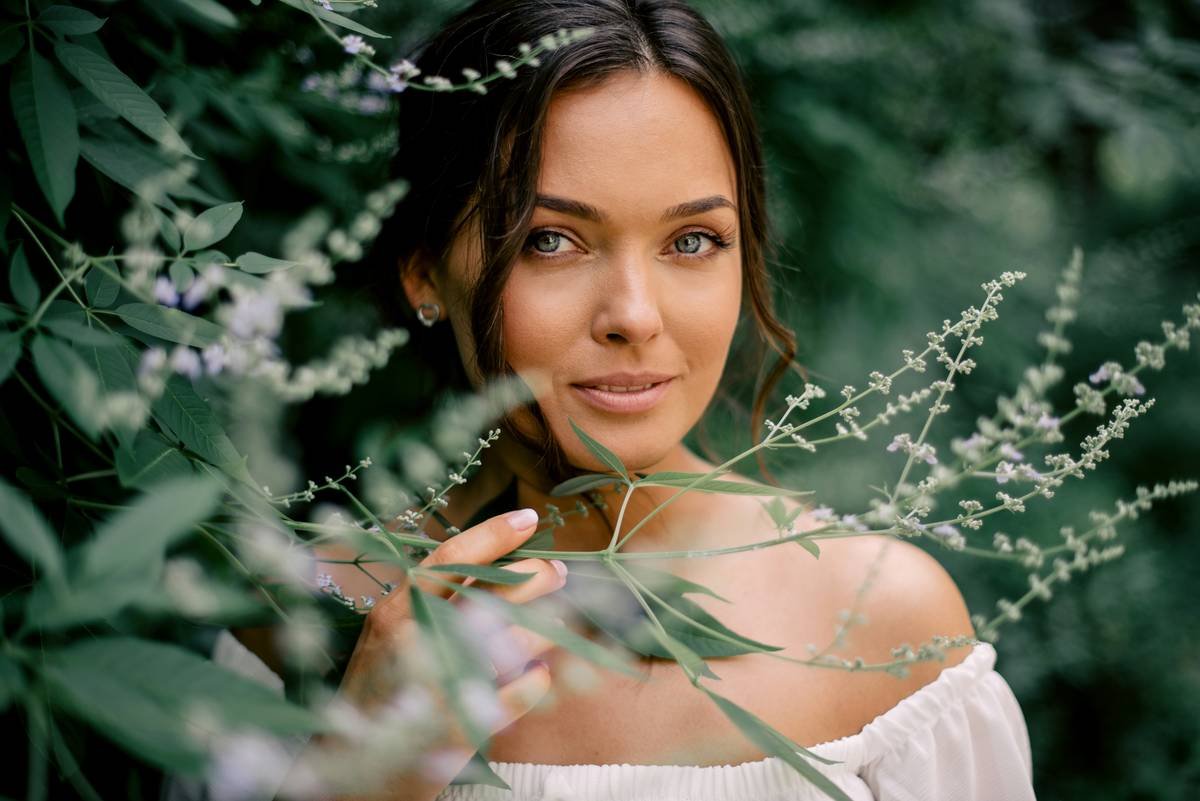 A woman with brown hair among green foliage