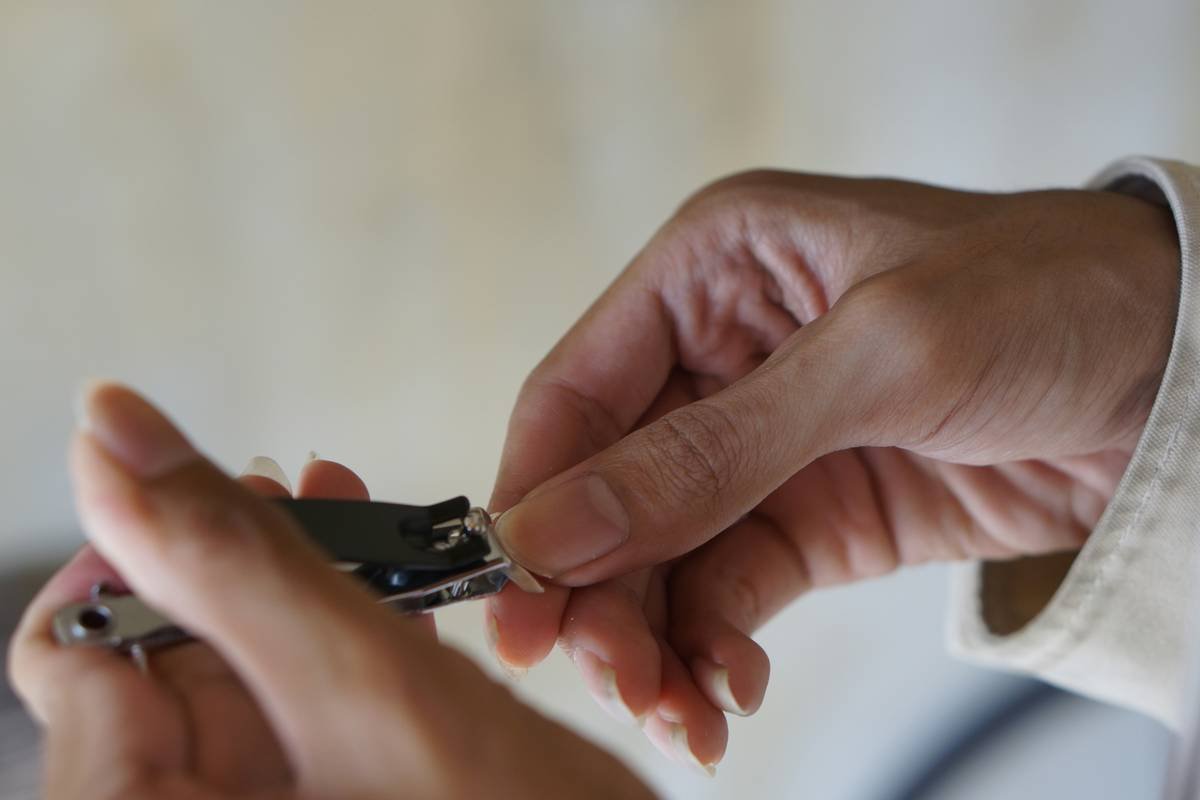 Close up of a man cutting his fingernail using nail clipper