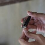 Close up of a man cutting his fingernail using nail clipper