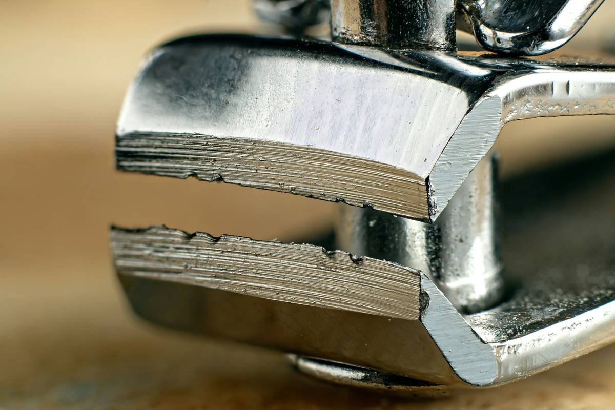 Closeup, focus stacked, macro shot of a chrome masculine dirty nail cutter on wood.