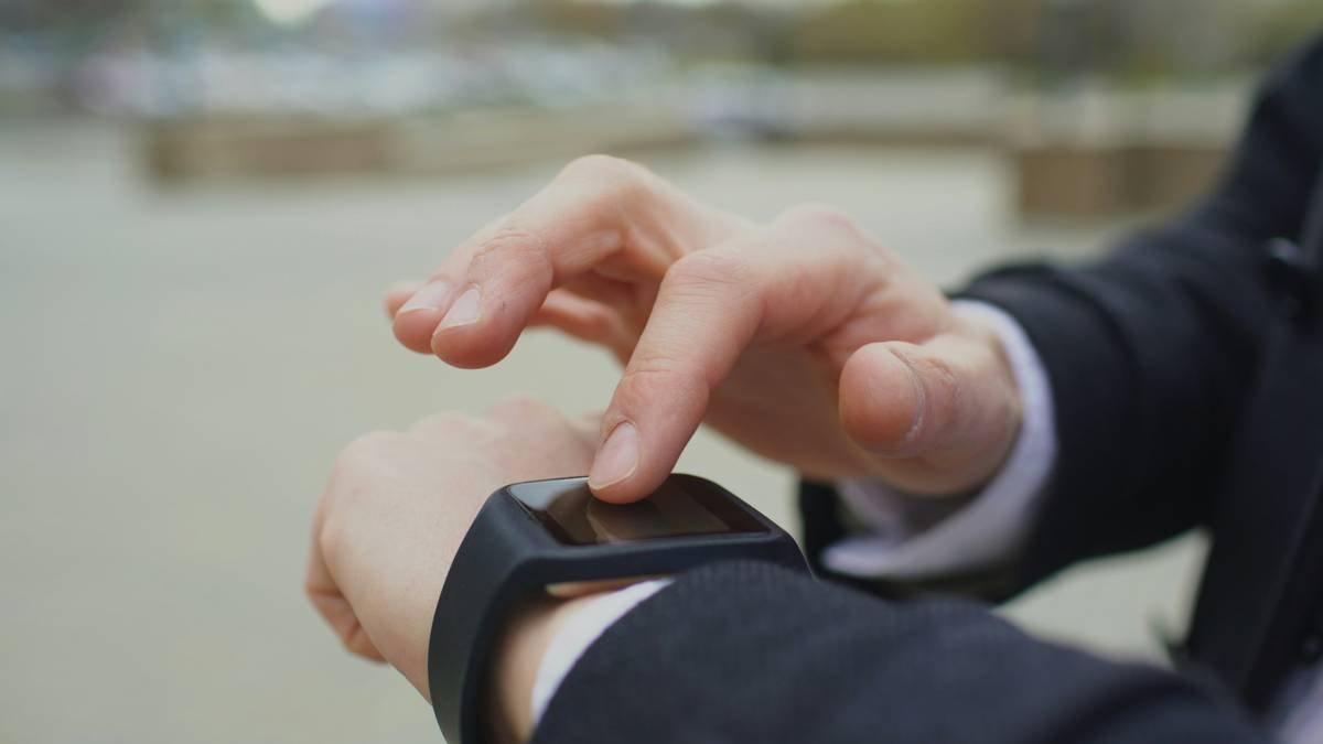 Closeup of businessman using his smartwatch touchscreen standing on street