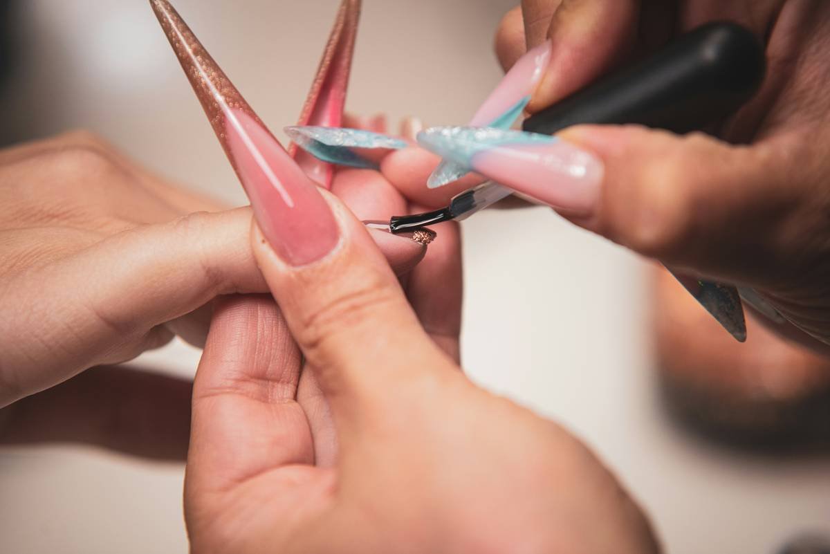 close-up of hand cleaning nail clipper blades with alcohol-soaked brush for nail clipper cleaning guide